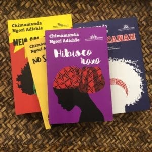 4 livros da Chimamanda espalhados sobre uma bandeja de palha